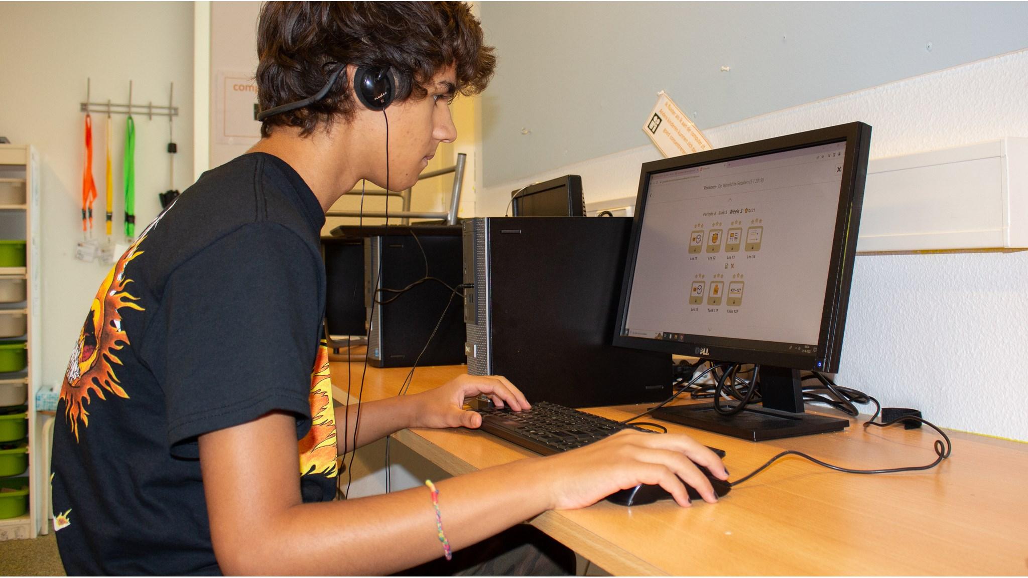 Een leerling van Kindcentrum Montessori Hoorn werkt aan zijn computer met hoofdtelefoon in de klas. Een leerling van Kindcentrum Montessori Hoorn werkt aan zijn computer met hoofdtelefoon in de klas.