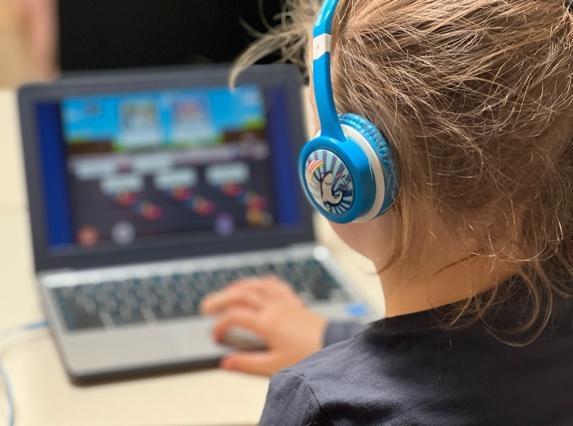 Een leerling van OBS Dirk van Dijk in Kampen leert met behulp van een laptop en koptelefoon.