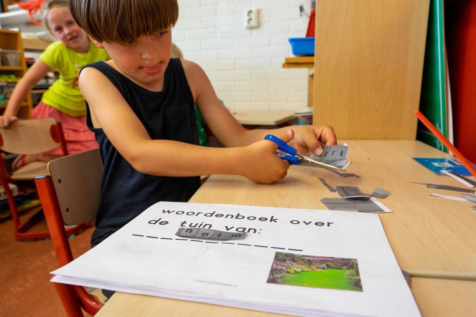Een leerling van Openbare Basisschool de Cocon in Alkmaar knipt woorden uit voor een schoolproject. Een leerling van Openbare Basisschool de Cocon in Alkmaar knipt woorden uit voor een schoolproject.