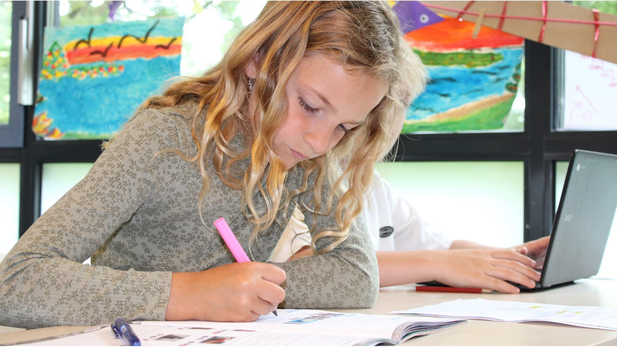Een leerling van Openbare Basisschool de Kraaienboom in Benningbroek is gefocust aan het werk met een boek en een pen. Een leerling van Openbare Basisschool de Kraaienboom in Benningbroek is gefocust aan het werk met een boek en een pen.