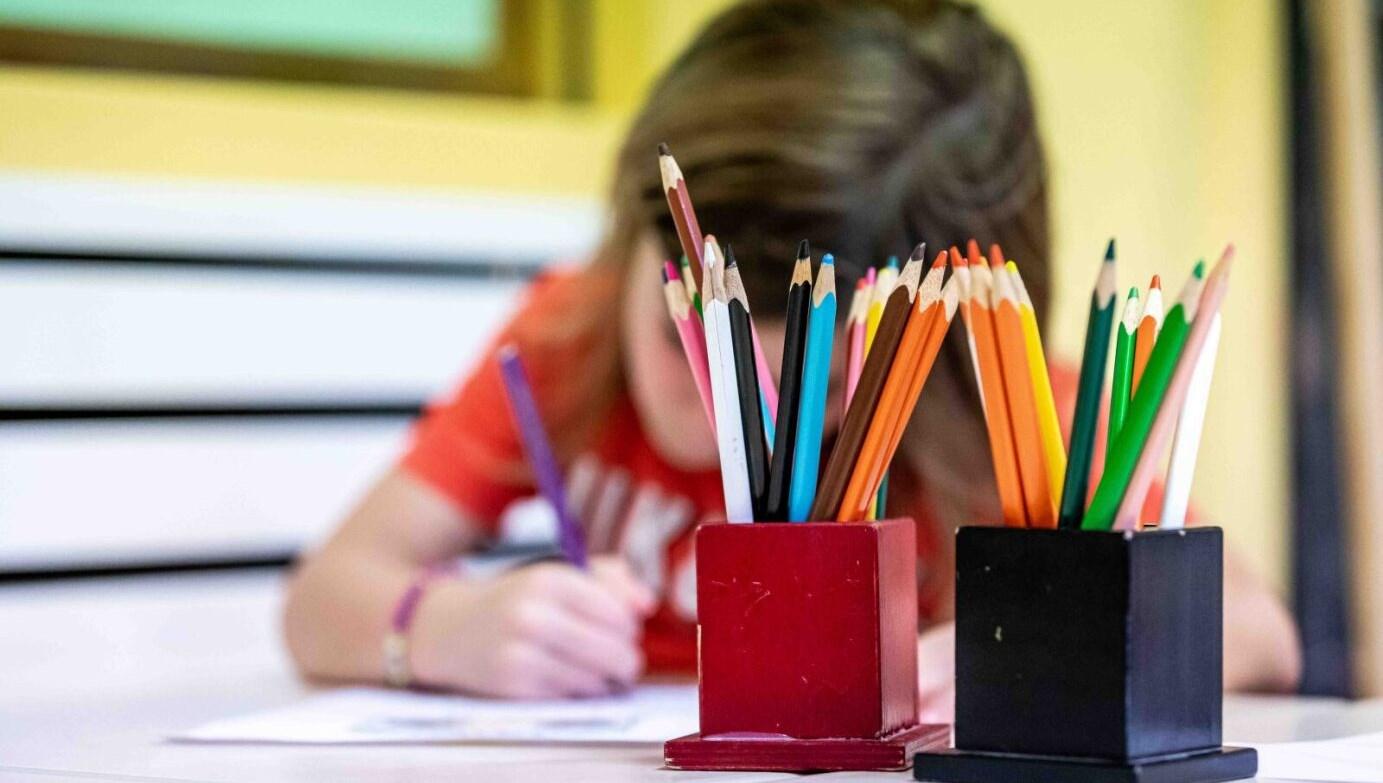 Een leerling van Sterrenpad 't Ven in Venlo is bezig met tekenen met kleurpotloden op een tafel.