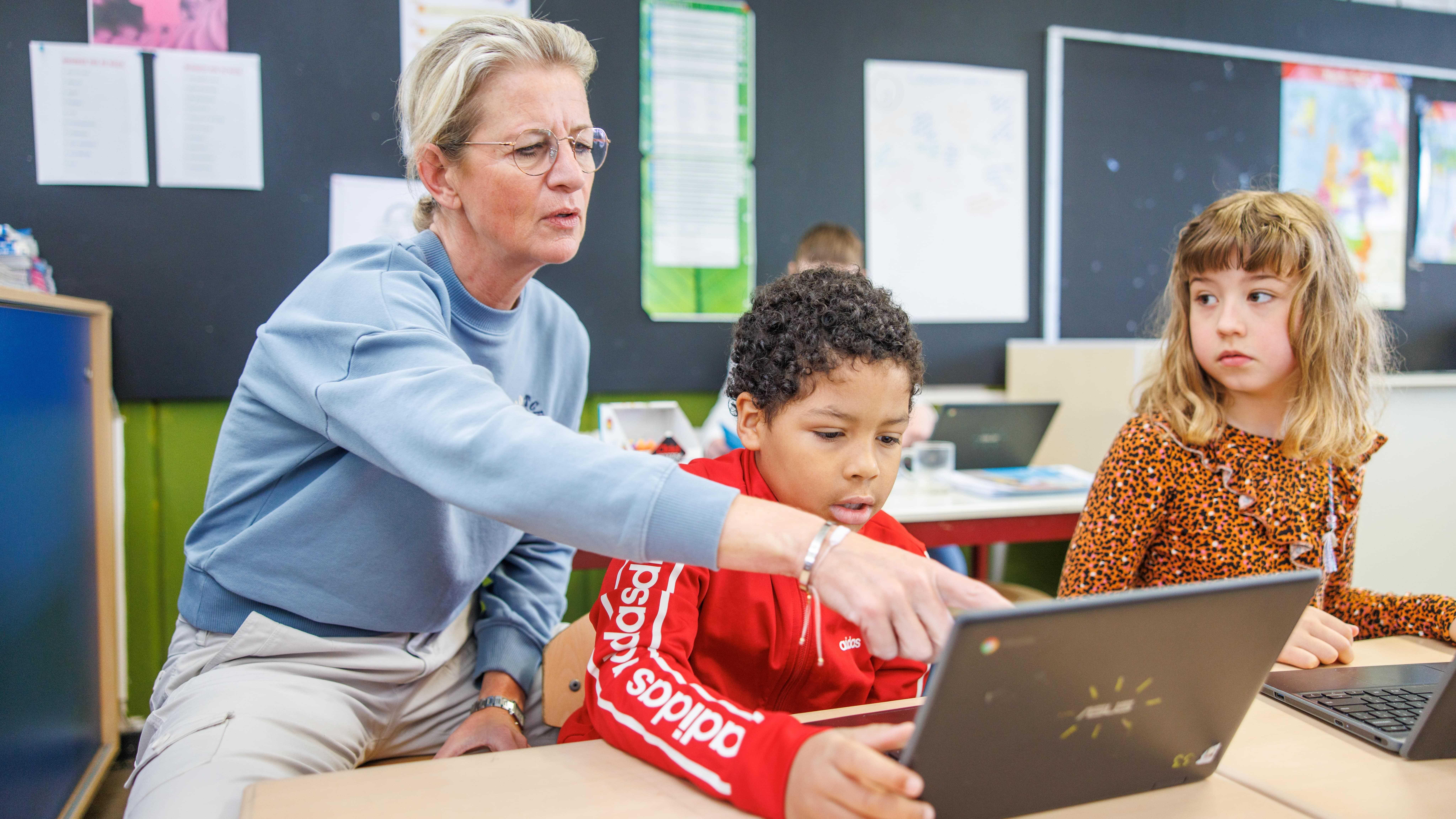 Een lerares helpt een leerling met zijn laptop in Christelijke Basisschool De Wingerd in Ridderkerk. Een lerares helpt een leerling met zijn laptop in Christelijke Basisschool De Wingerd in Ridderkerk.