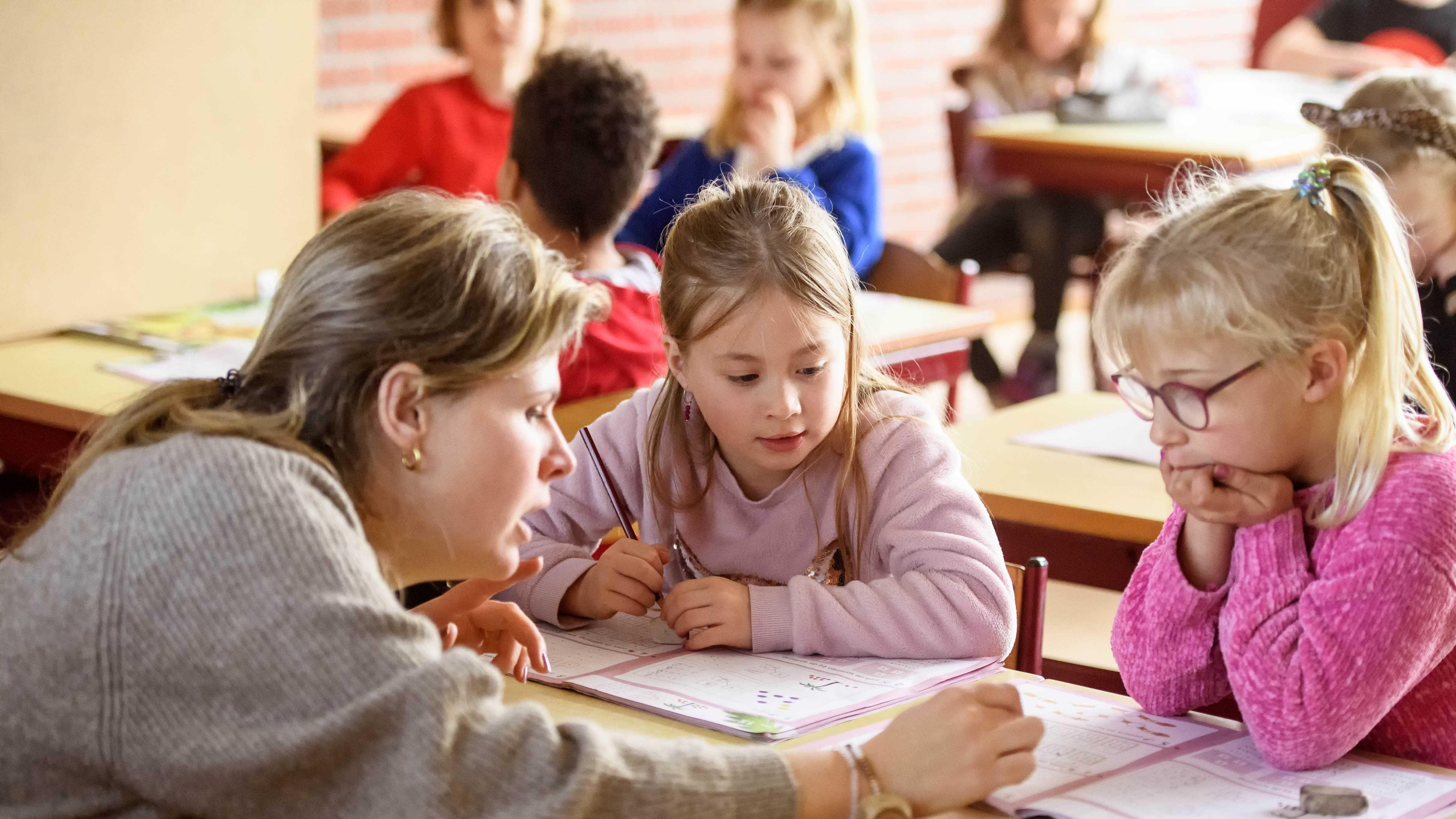 Een lerares helpt leerlingen met hun huiswerk in de klas van Basisschool St Wulfram in Hoogwoud. Een lerares helpt leerlingen met hun huiswerk in de klas van Basisschool St Wulfram in Hoogwoud.