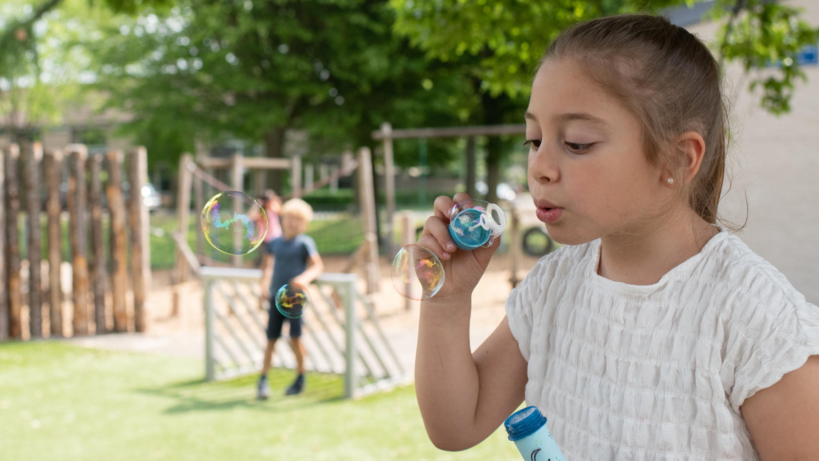 Een meisje blaast bellen op het schoolplein van De Vliegeniers in Barneveld. Een meisje blaast bellen op het schoolplein van De Vliegeniers in Barneveld.