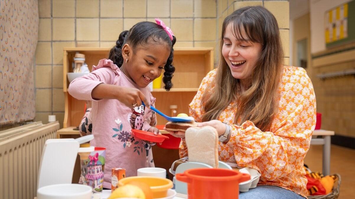 Een meisje en een begeleider spelen samen met speelgoedeten in Kindcentrum Blijvliet in Rotterdam. Een meisje en een begeleider spelen samen met speelgoedeten in Kindcentrum Blijvliet in Rotterdam.