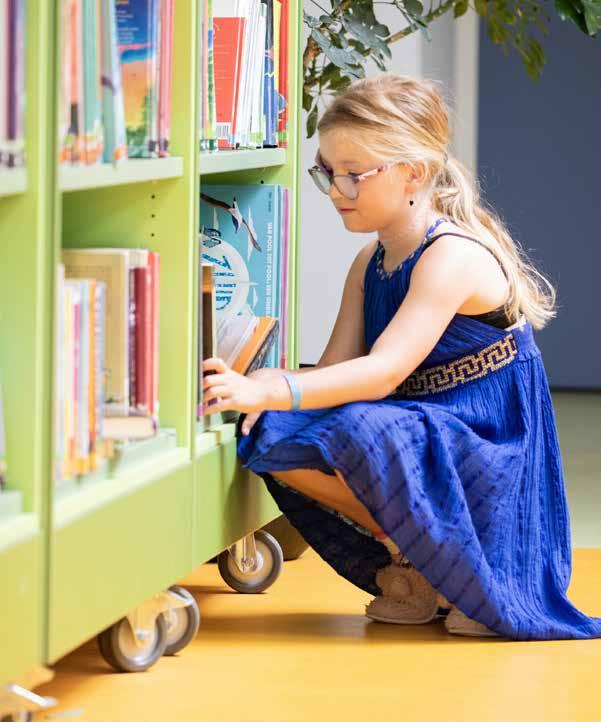 Een meisje in een blauwe jurk verplaatst boeken in de bibliotheek van basisschool Het Mozaïek in Houten. Een meisje in een blauwe jurk verplaatst boeken in de bibliotheek van basisschool Het Mozaïek in Houten.