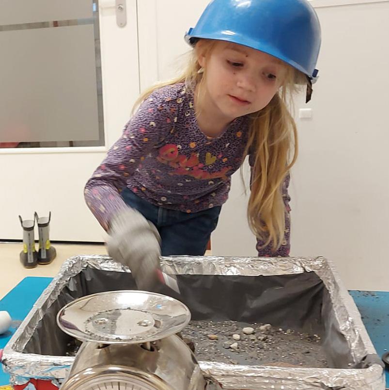 Een meisje in een elektrisch blauw helmpje speelt met een werktafel op OBS Het Anker in Wijk bij Duurstede.