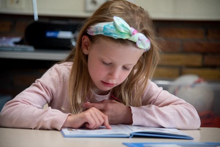 Een meisje leest een boek in de klas van Basisschool Wisperweide in Weesp. Een meisje leest een boek in de klas van Basisschool Wisperweide in Weesp.