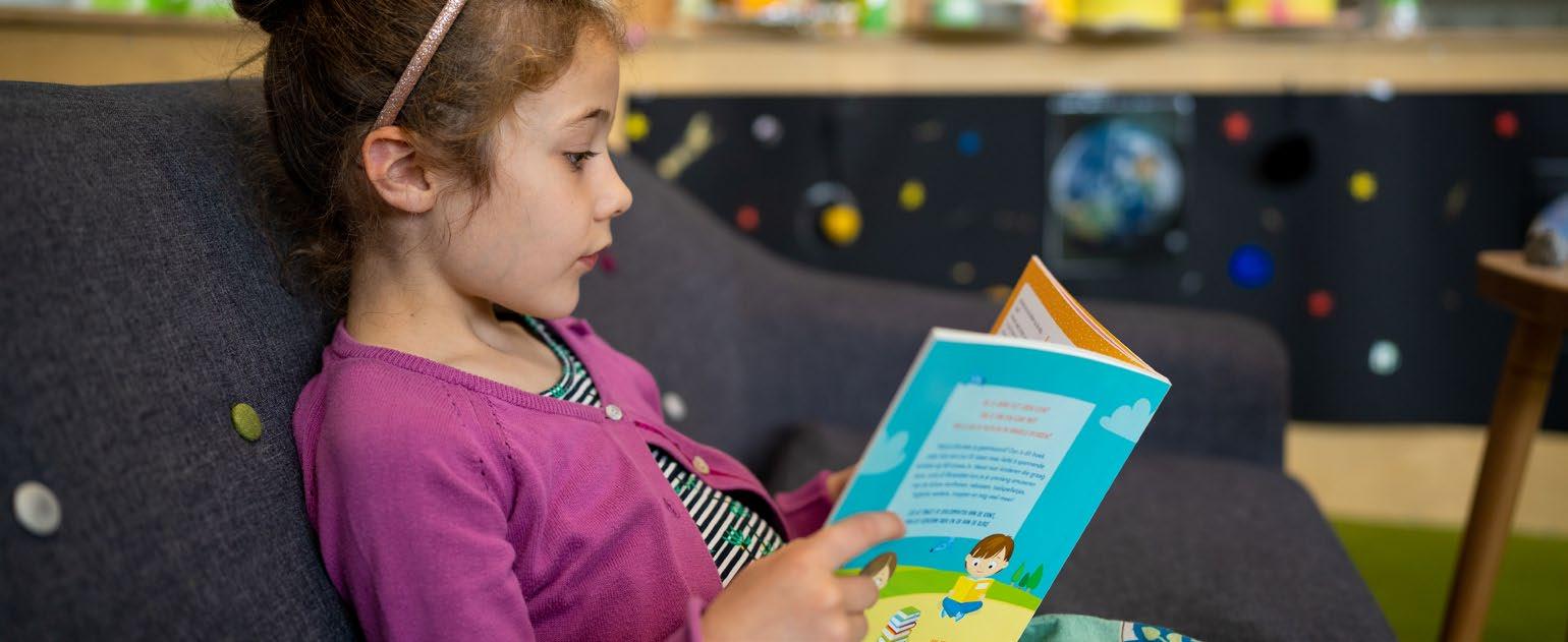 Een meisje leest een boek op een bank in de Synergieschool St Alfonsus voor basisonderwijs in Roermond. Een meisje leest een boek op een bank in de Synergieschool St Alfonsus voor basisonderwijs in Roermond.