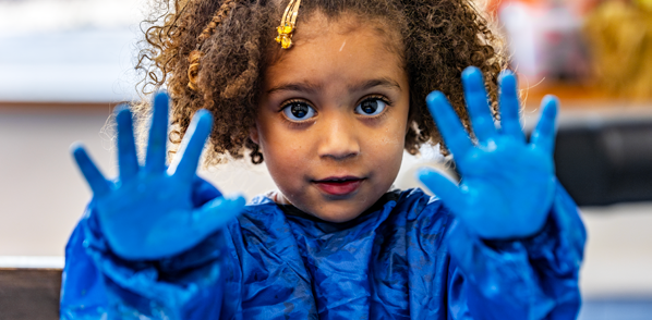 Een meisje met blauwe verf op haar handen in Integraal Kindcentrum de Regenboog in Bemmel. Een meisje met blauwe verf op haar handen in Integraal Kindcentrum de Regenboog in Bemmel.