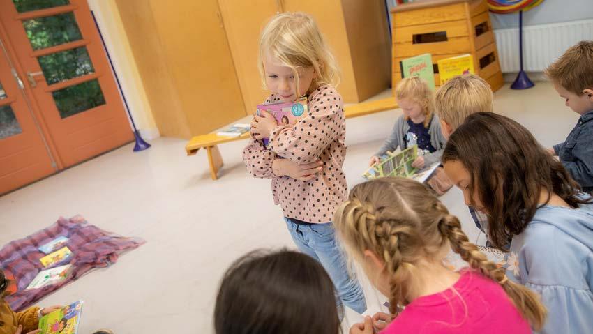 Een meisje met een boek omarmt staat in de klas van P.C. basisschool De Bolster in Amersfoort, terwijl andere kinderen aan het lezen zijn. Een meisje met een boek omarmt staat in de klas van P.C. basisschool De Bolster in Amersfoort, terwijl andere kinderen aan het lezen zijn.
