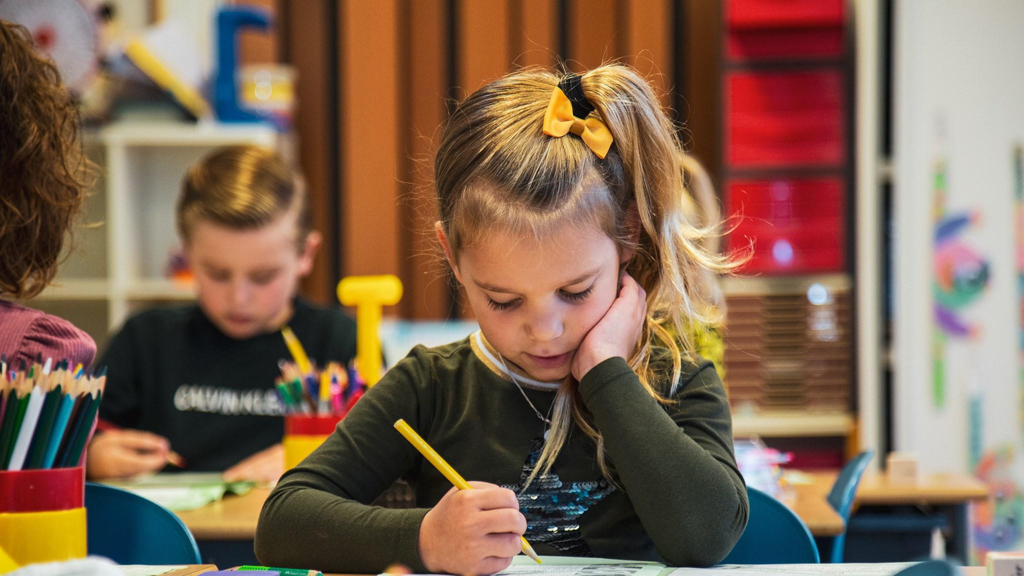 Een meisje met een gele haarband maakt huiswerk in de klas van RK Basisschool Schuttevaer in Hansweert.