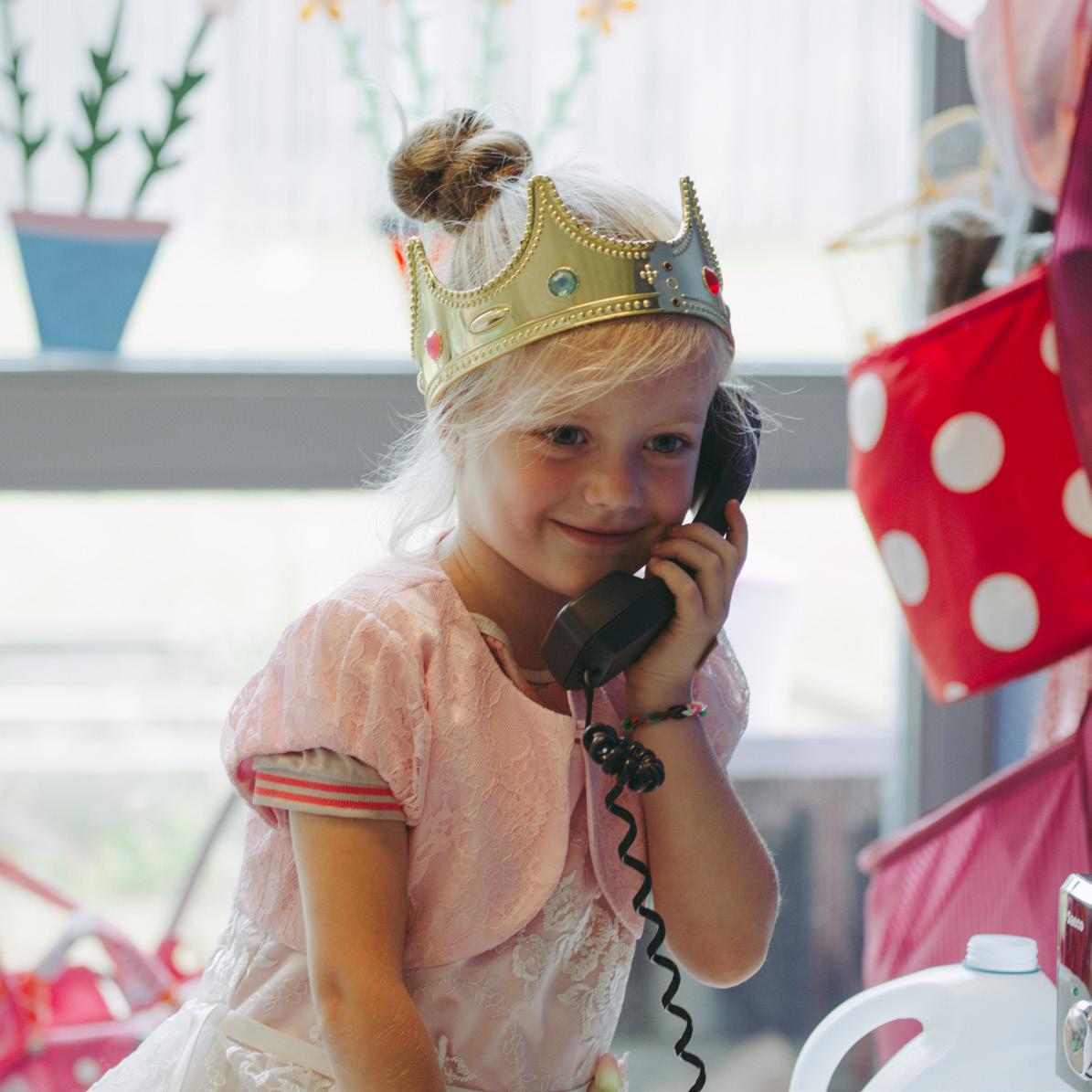 Een meisje met een kroon praat vrolijk aan de telefoon in Openbare Basisschool De Flint in Deventer. Een meisje met een kroon praat vrolijk aan de telefoon in Openbare Basisschool De Flint in Deventer.