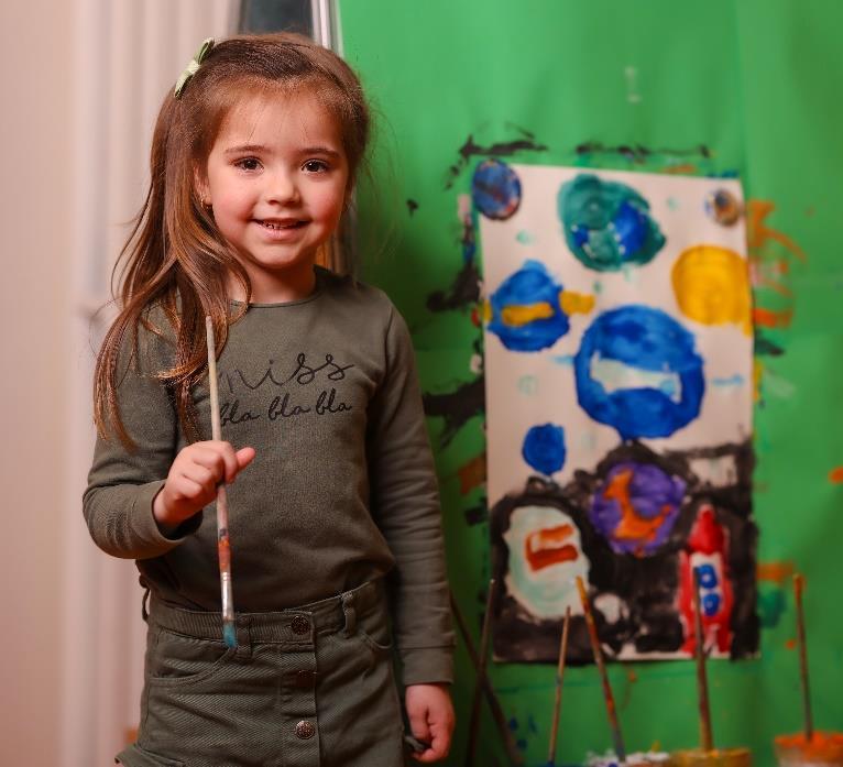 Een meisje met een kwast poseert trots naast haar kunstwerk in IKC Bernadette Maria in Delft. Een meisje met een kwast poseert trots naast haar kunstwerk in IKC Bernadette Maria in Delft.