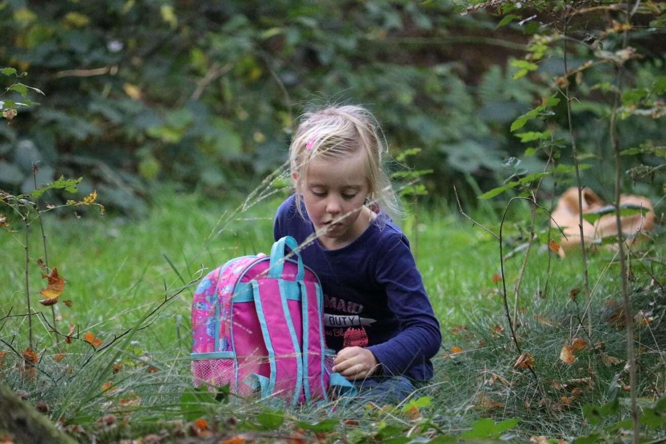 Een meisje met een roze rugzak speelt in de natuur nabij Het Avontuur in Dalfsen.