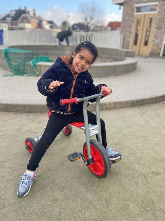 Een meisje rijdt lachend op een driewieler op het schoolplein van Hannie Schaft Basisschool in Zandvoort. Een meisje rijdt lachend op een driewieler op het schoolplein van Hannie Schaft Basisschool in Zandvoort.