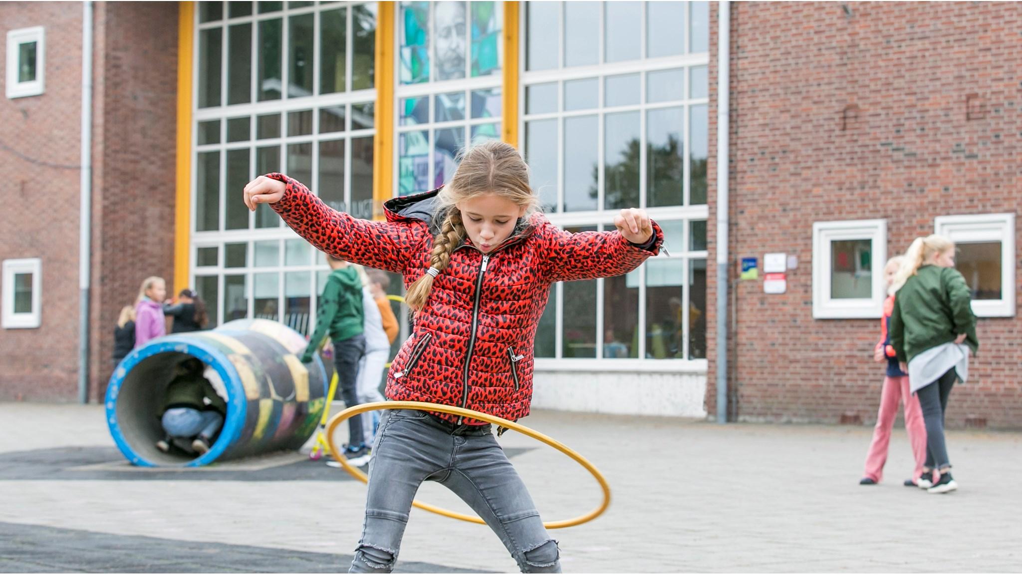 Een meisje speelt met een hoelahoep op het schoolplein van de Jan Ligthartschool in Wapenveld. Een meisje speelt met een hoelahoep op het schoolplein van de Jan Ligthartschool in Wapenveld.