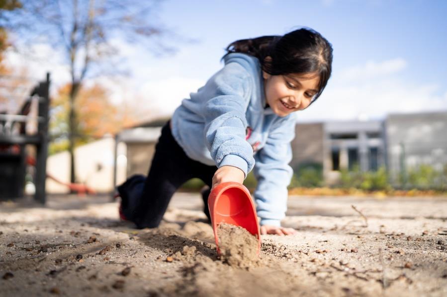 Een meisje speelt met een schepje op het schoolplein van Openbare Basisschool De Samensprong in Grubbenvorst. Een meisje speelt met een schepje op het schoolplein van Openbare Basisschool De Samensprong in Grubbenvorst.