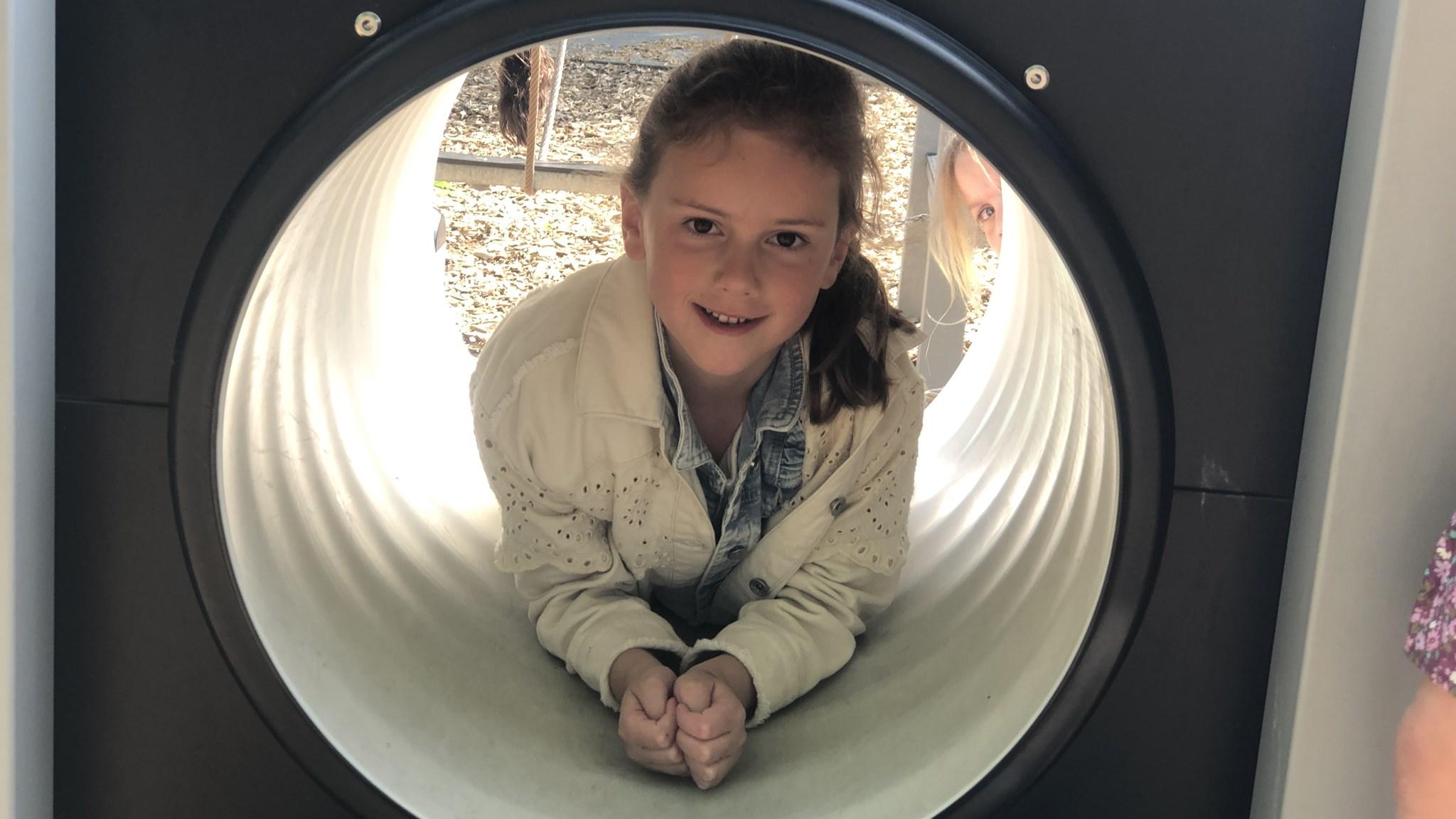 Een meisje speelt vrolijk in de tunnel op het schoolplein van de Odaschool voor basisonderwijs Boshoven Weert. Een meisje speelt vrolijk in de tunnel op het schoolplein van de Odaschool voor basisonderwijs Boshoven Weert.