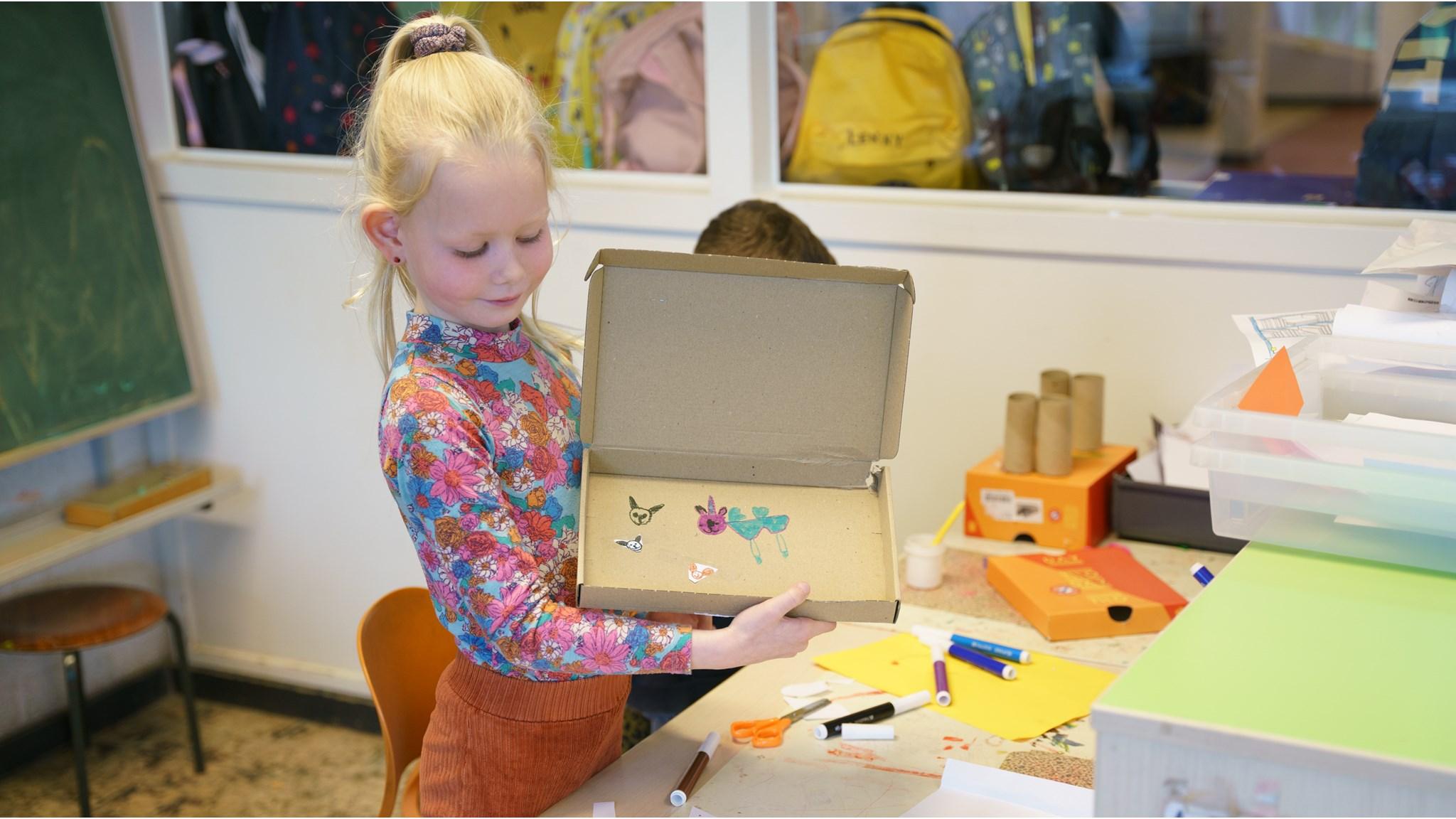 Een meisje toont trots haar kunstwerk in de klas van RK Basisschool St Antonius in Maren-Kessel. Een meisje toont trots haar kunstwerk in de klas van RK Basisschool St Antonius in Maren-Kessel.
