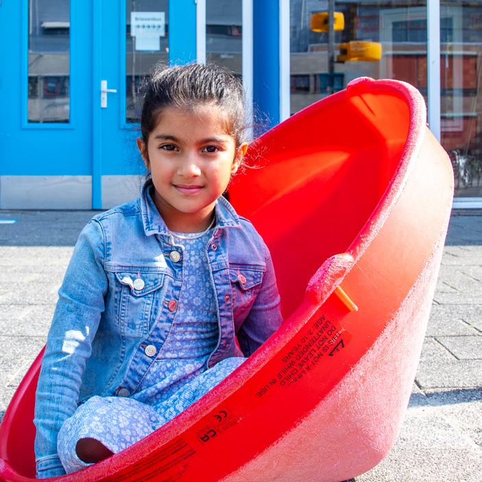 Een meisje zit in een rode glijbaan op het schoolplein van De Wereldwijzer in Alphen aan den Rijn. Een meisje zit in een rode glijbaan op het schoolplein van De Wereldwijzer in Alphen aan den Rijn.