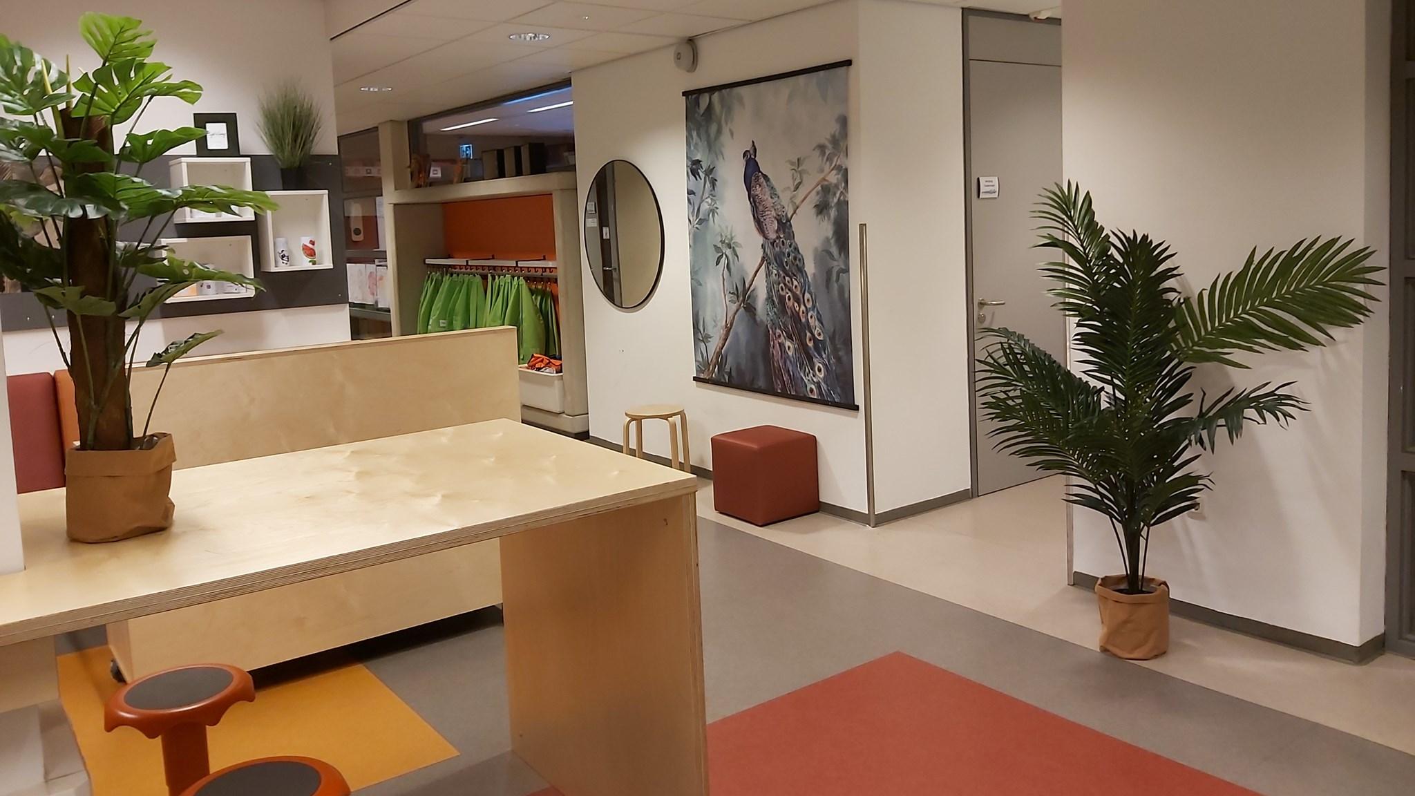 Een moderne binnenruimte van Openbare Basisschool De Tuimelaar in Veghel met planten en een kunstwerk aan de muur. Een moderne binnenruimte van Openbare Basisschool De Tuimelaar in Veghel met planten en een kunstwerk aan de muur.