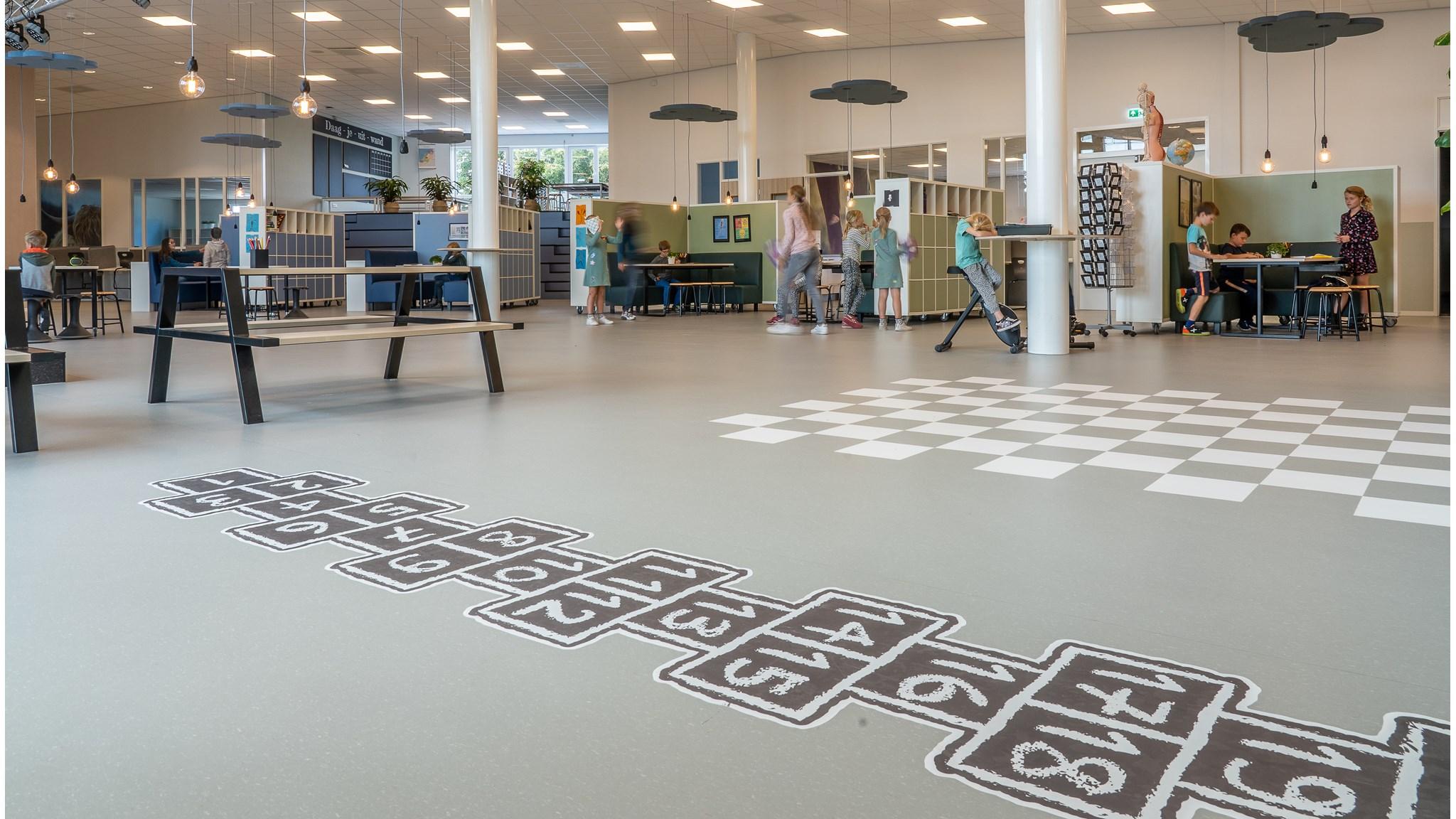 Een speelse leeromgeving binnen Kindcentrum De Uitdaging in Nijmegen, met een vloerontwerp voor hinkelen en een schaakbord. Een speelse leeromgeving binnen Kindcentrum De Uitdaging in Nijmegen, met een vloerontwerp voor hinkelen en een schaakbord.