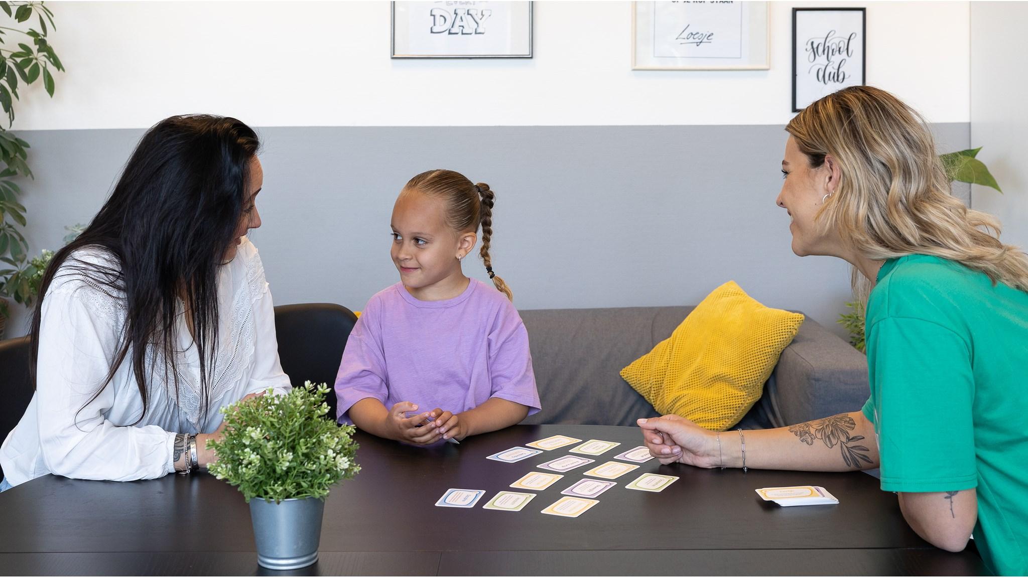 Foto van een kind dat spelletjes speelt met twee volwassenen in IKC De Achtsprong, Zoetermeer. Foto van een kind dat spelletjes speelt met twee volwassenen in IKC De Achtsprong, Zoetermeer.