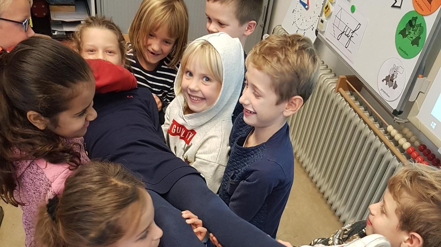 Groep blije kinderen omhelst elkaar in de klas van IKC De Stek in Est. Groep blije kinderen omhelst elkaar in de klas van IKC De Stek in Est.