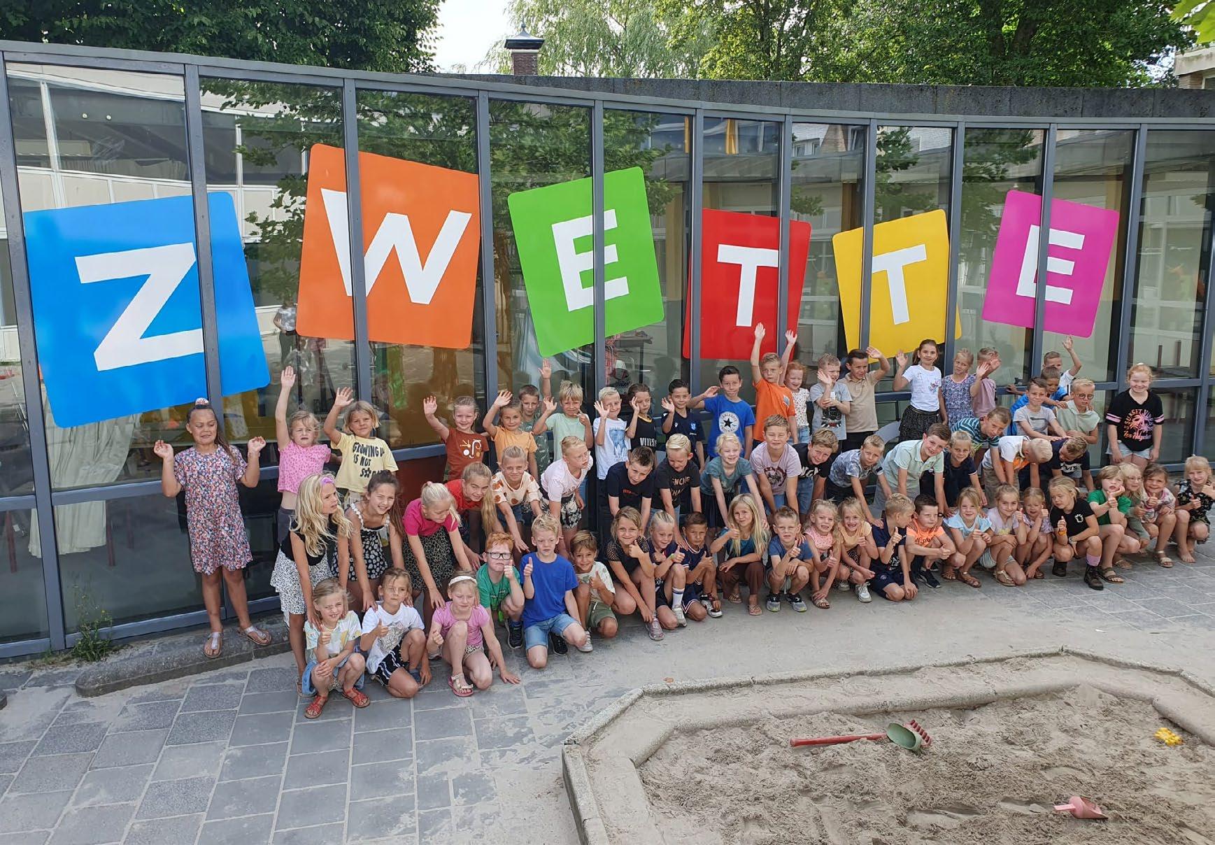 Groep kinderen poseert blij voor de Zwetteschool in Sneek met kleurrijke letters die de schoolnaam vormen. Groep kinderen poseert blij voor de Zwetteschool in Sneek met kleurrijke letters die de schoolnaam vormen.
