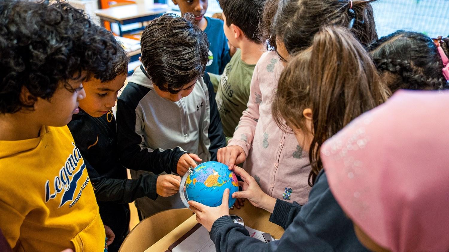 Groep kinderen zijn bezig met een globe tijdens een les op de Ikra school in Dordrecht.