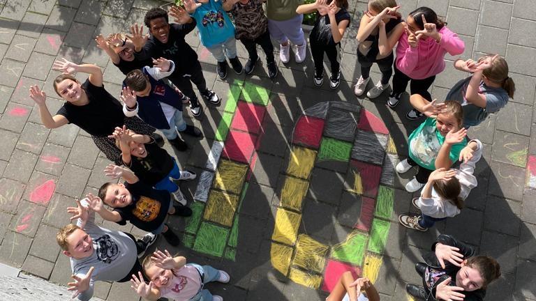 Groep leerlingen van Kindcentrum Manjefiek in Maastricht poseert met gespreide handen op het schoolplein. Groep leerlingen van Kindcentrum Manjefiek in Maastricht poseert met gespreide handen op het schoolplein.