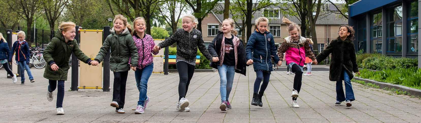Groep vrolijke kinderen die hand in hand rennen op het schoolplein van Het Baken I in Veenendaal. Groep vrolijke kinderen die hand in hand rennen op het schoolplein van Het Baken I in Veenendaal.