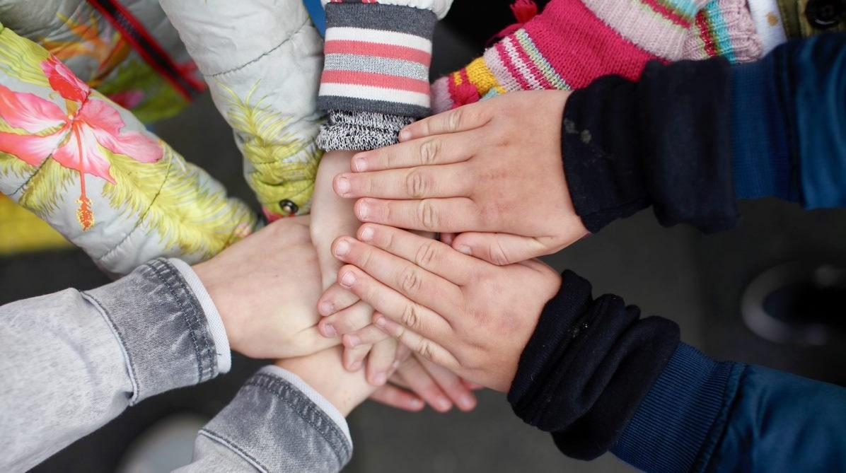 Handen van kinderen die samenkomen op het schoolplein van obs Prinses Wilhelmina in Lexmond.