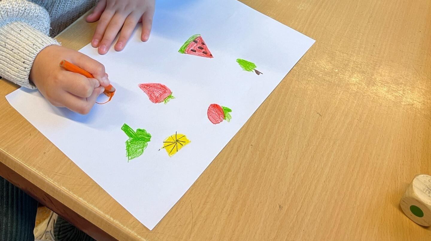 Het kind tekent kleurrijke vruchten op papier aan Openbare Basisschool De Rietkraag in Oostzaan. Het kind tekent kleurrijke vruchten op papier aan Openbare Basisschool De Rietkraag in Oostzaan.