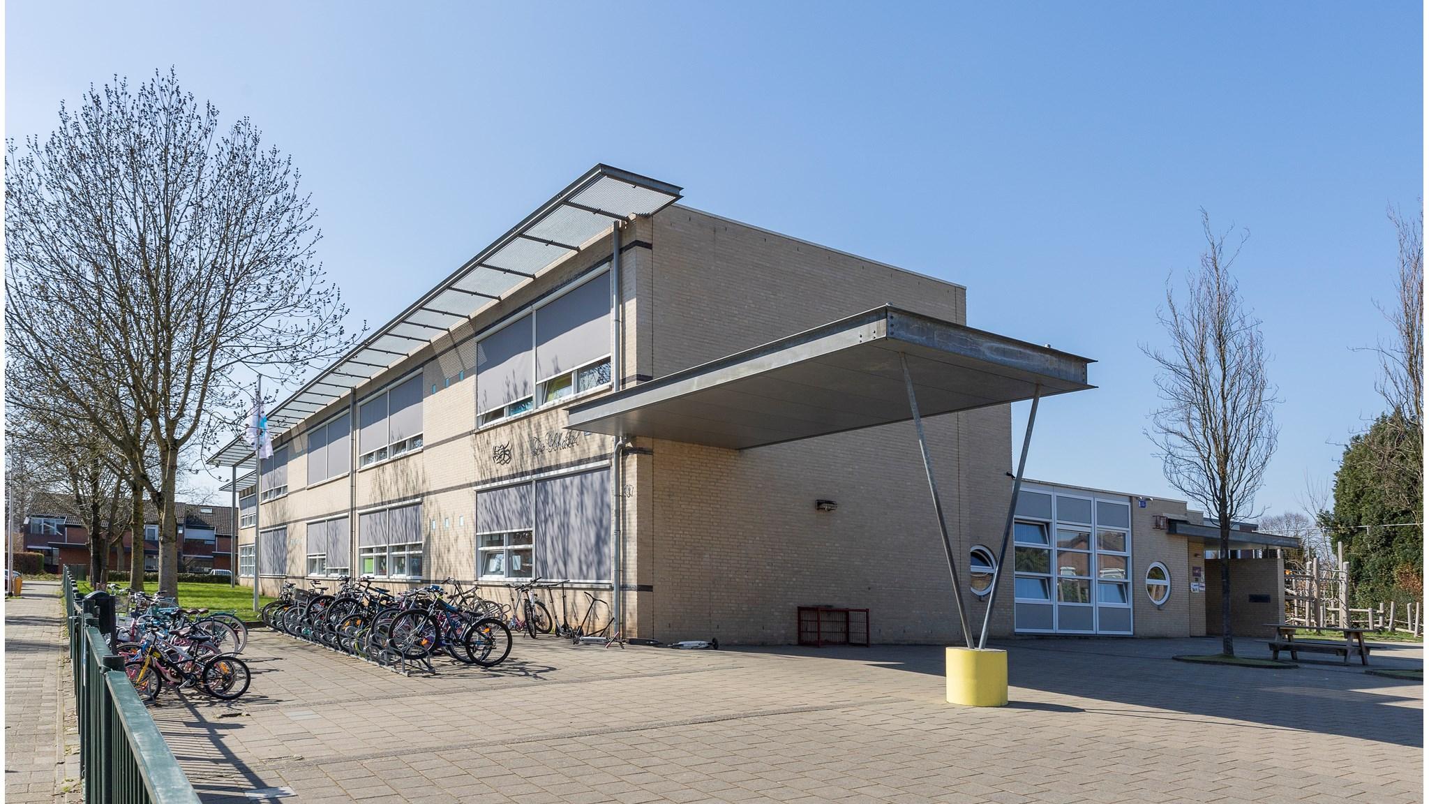 Het schoolgebouw van Basisschool De Schakel in Kerkrade met een overzicht van het schoolplein en fietsenstalling. Het schoolgebouw van Basisschool De Schakel in Kerkrade met een overzicht van het schoolplein en fietsenstalling.