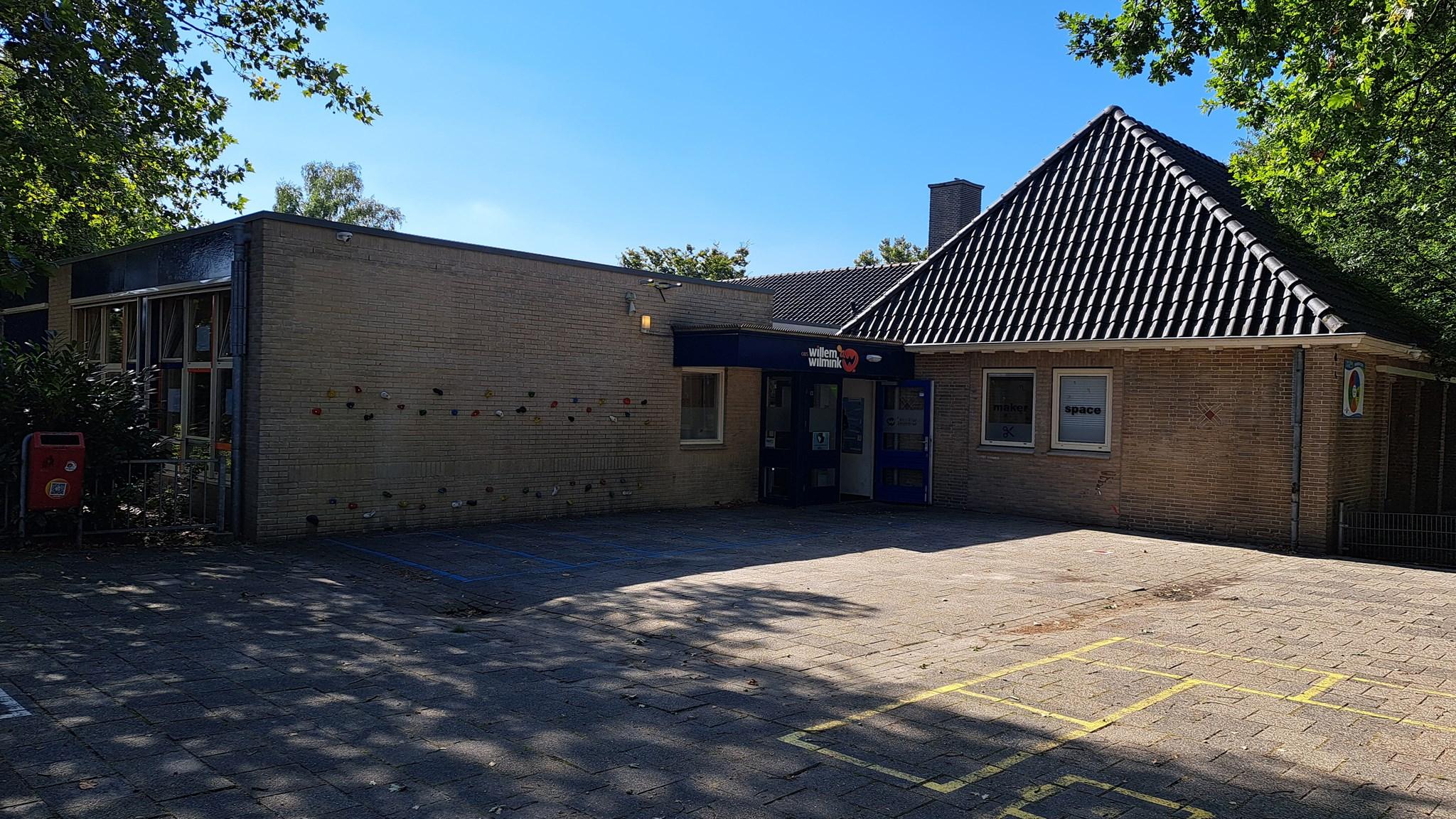 Het schoolgebouw van obs Willem Wilmink in Enschede met een helder blauwe lucht en een schoolplein. Het schoolgebouw van obs Willem Wilmink in Enschede met een helder blauwe lucht en een schoolplein.