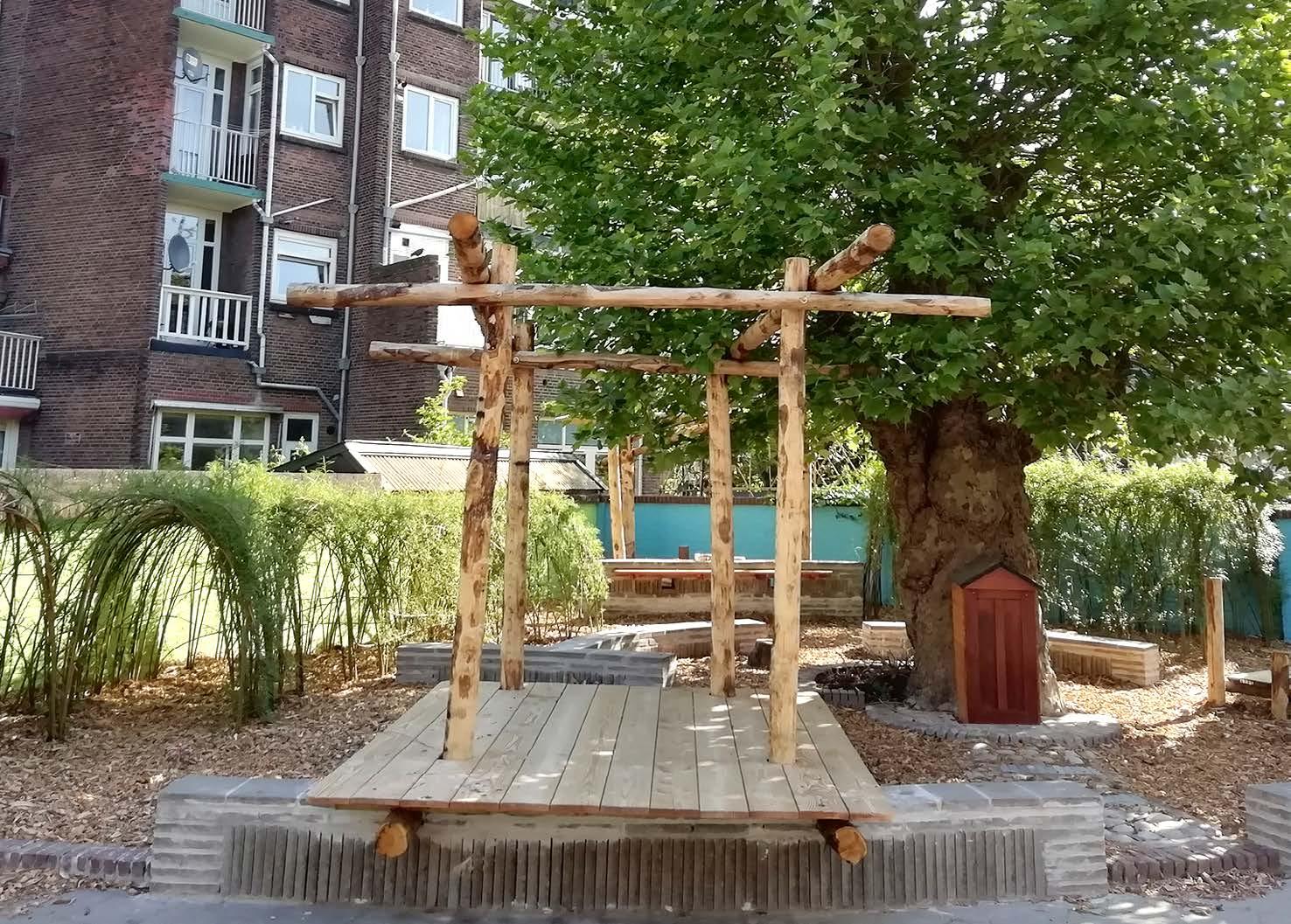 Het schoolplein van Avonturijn in Vlaardingen met een houten speelstructuur onder een grote boom. Het schoolplein van Avonturijn in Vlaardingen met een houten speelstructuur onder een grote boom.