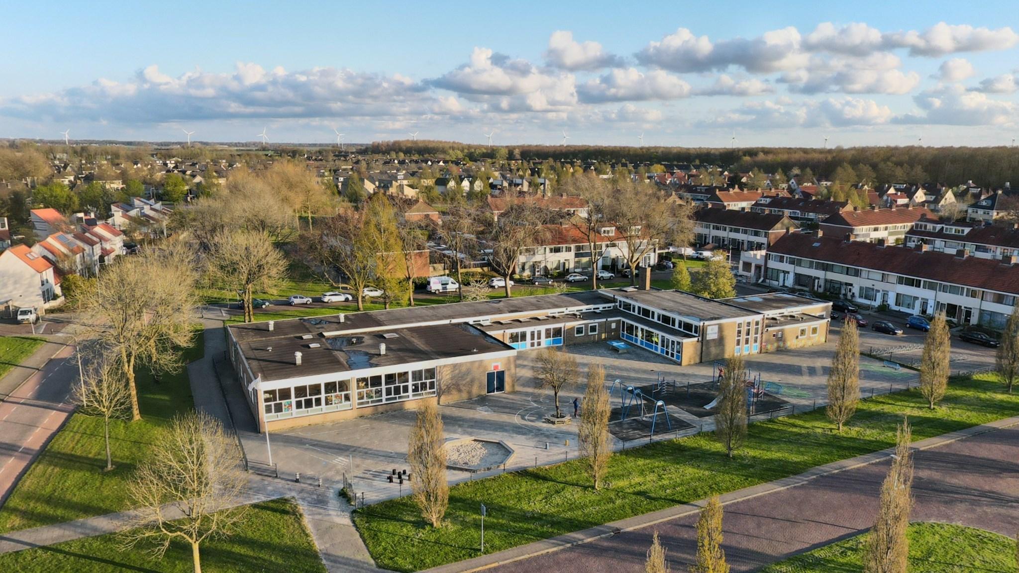 Het schoolplein van De Golfslag in Swifterbant, omgeven door groene bomen en huizen. Het schoolplein van De Golfslag in Swifterbant, omgeven door groene bomen en huizen.