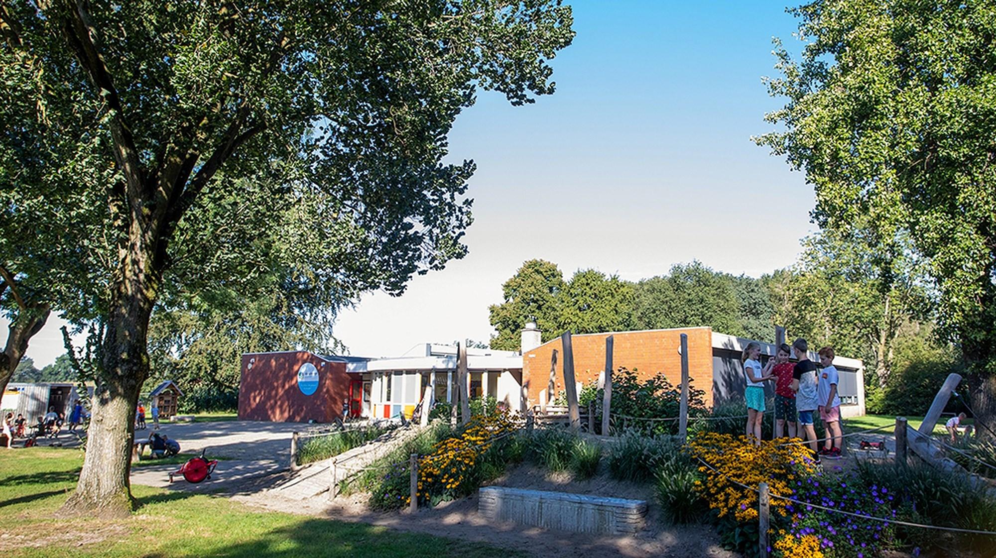 Het schoolplein van De Sprenge Emst in Emst, met kinderen die spelen in een groene omgeving. Het schoolplein van De Sprenge Emst in Emst, met kinderen die spelen in een groene omgeving.