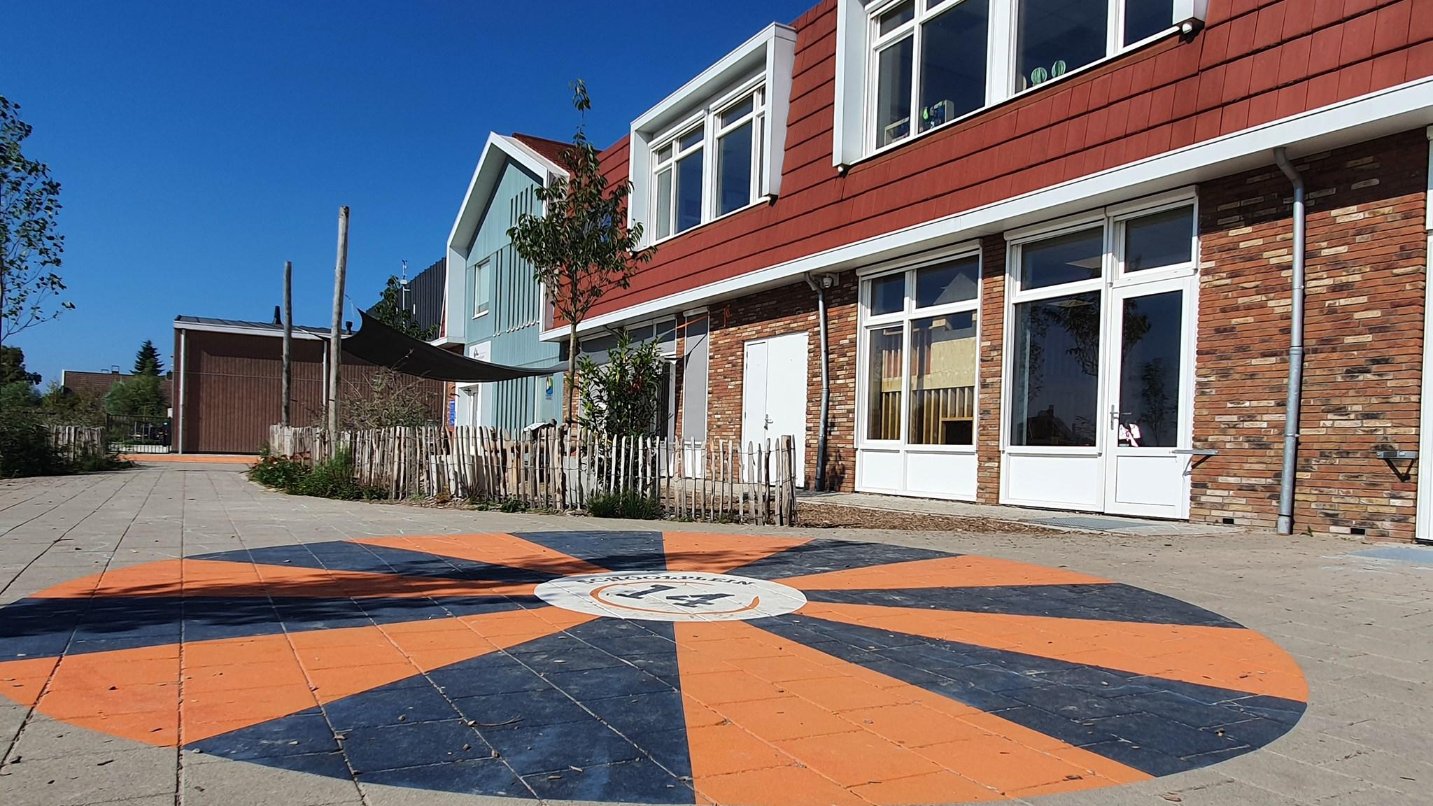 Het schoolplein van Openbare Basisschool De Koningsspil in Oosthuizen met een kleurrijk speelvlak.