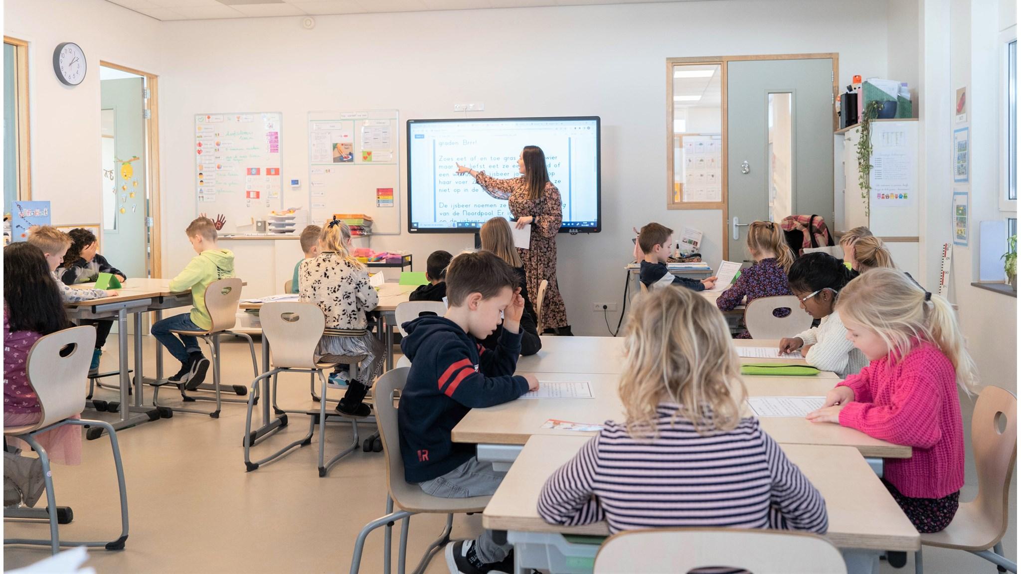 In de klas van KC Koningskwartier in Zevenhuizen (Zuid-Holland) zijn leerlingen actief bezig met hun werk terwijl de docente instructies geeft. In de klas van KC Koningskwartier in Zevenhuizen (Zuid-Holland) zijn leerlingen actief bezig met hun werk terwijl de docente instructies geeft.