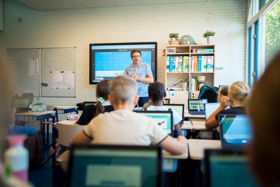 In de klas van Protestants Christelijke Basisschool het Kompas in Krimpen aan den IJssel legt de leraar een les uit aan leerlingen die voor zich uit kijken naar hun laptops. In de klas van Protestants Christelijke Basisschool het Kompas in Krimpen aan den IJssel legt de leraar een les uit aan leerlingen die voor zich uit kijken naar hun laptops.