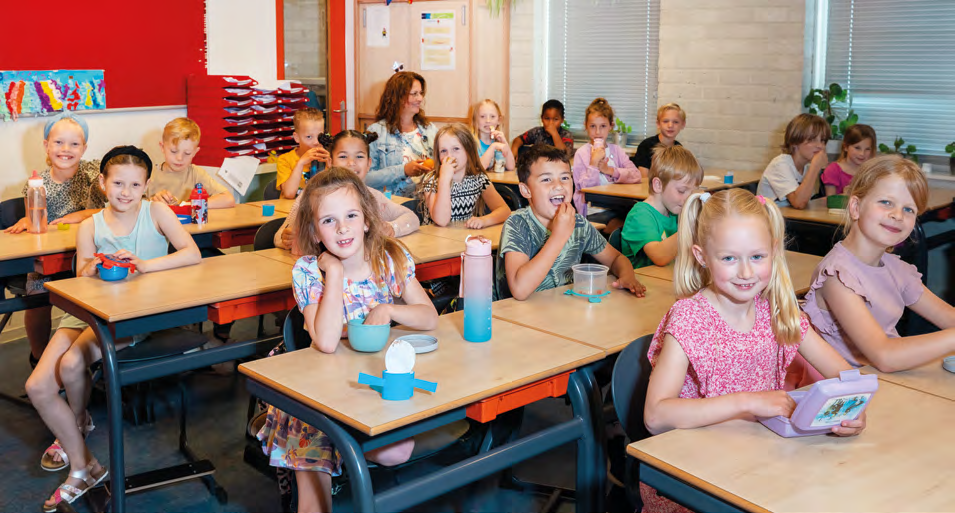 In het klaslokaal van IKC de Driemaster in Hoek van Holland zitten blije kinderen samen met hun juf. In het klaslokaal van IKC de Driemaster in Hoek van Holland zitten blije kinderen samen met hun juf.