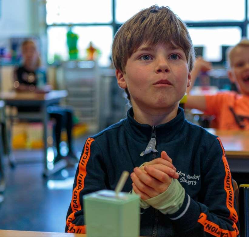 Jongen met een handverband en een drankje in de klas van de Antoniusschool in Kudelstaart. Jongen met een handverband en een drankje in de klas van de Antoniusschool in Kudelstaart.