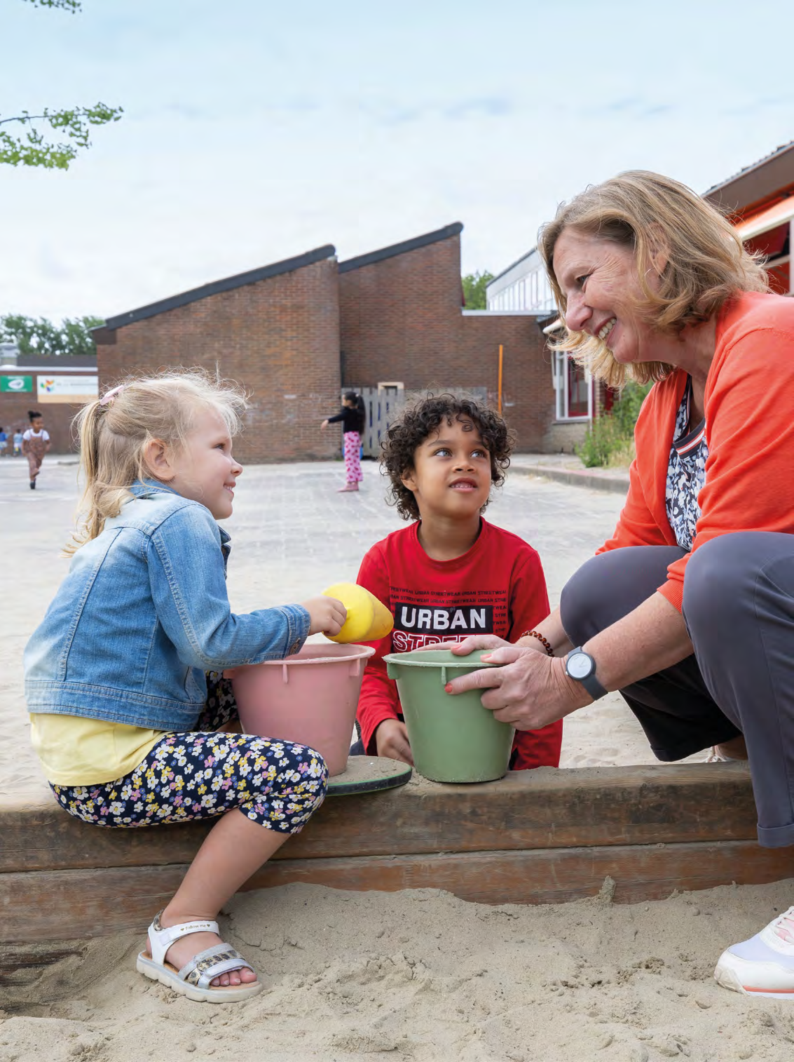Kindcentrum De Buskes in Rotterdam: kinderen spelen met zand en manden op het schoolplein. Kindcentrum De Buskes in Rotterdam: kinderen spelen met zand en manden op het schoolplein.