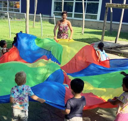 Kindcentrum De Duif in Heiloo: kinderen spelen met een kleurrijke parachute op het schoolplein. Kindcentrum De Duif in Heiloo: kinderen spelen met een kleurrijke parachute op het schoolplein.