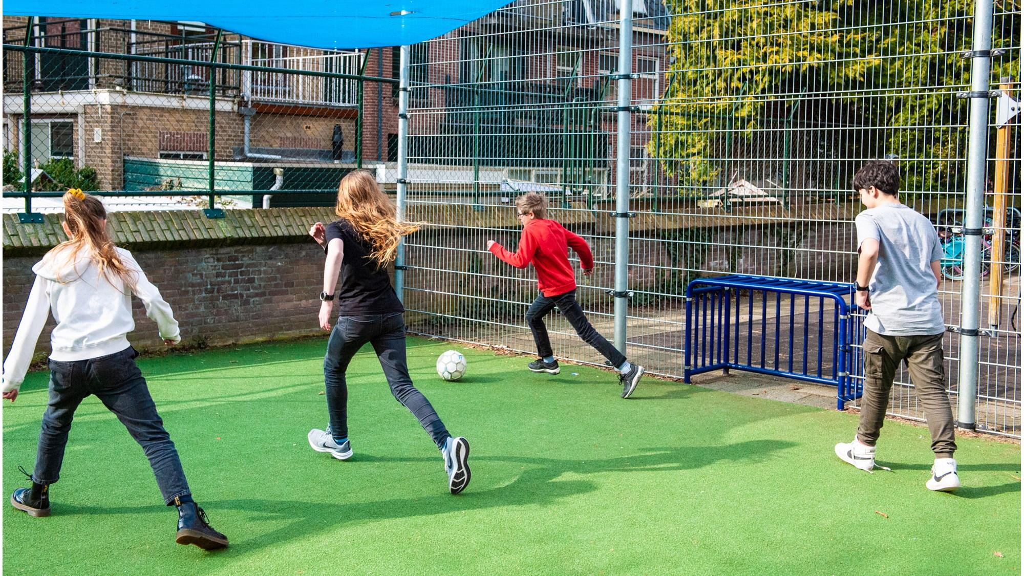 Kindcentrum De Heijberg in Rotterdam, kinderen spelen voetbal op het schoolplein.