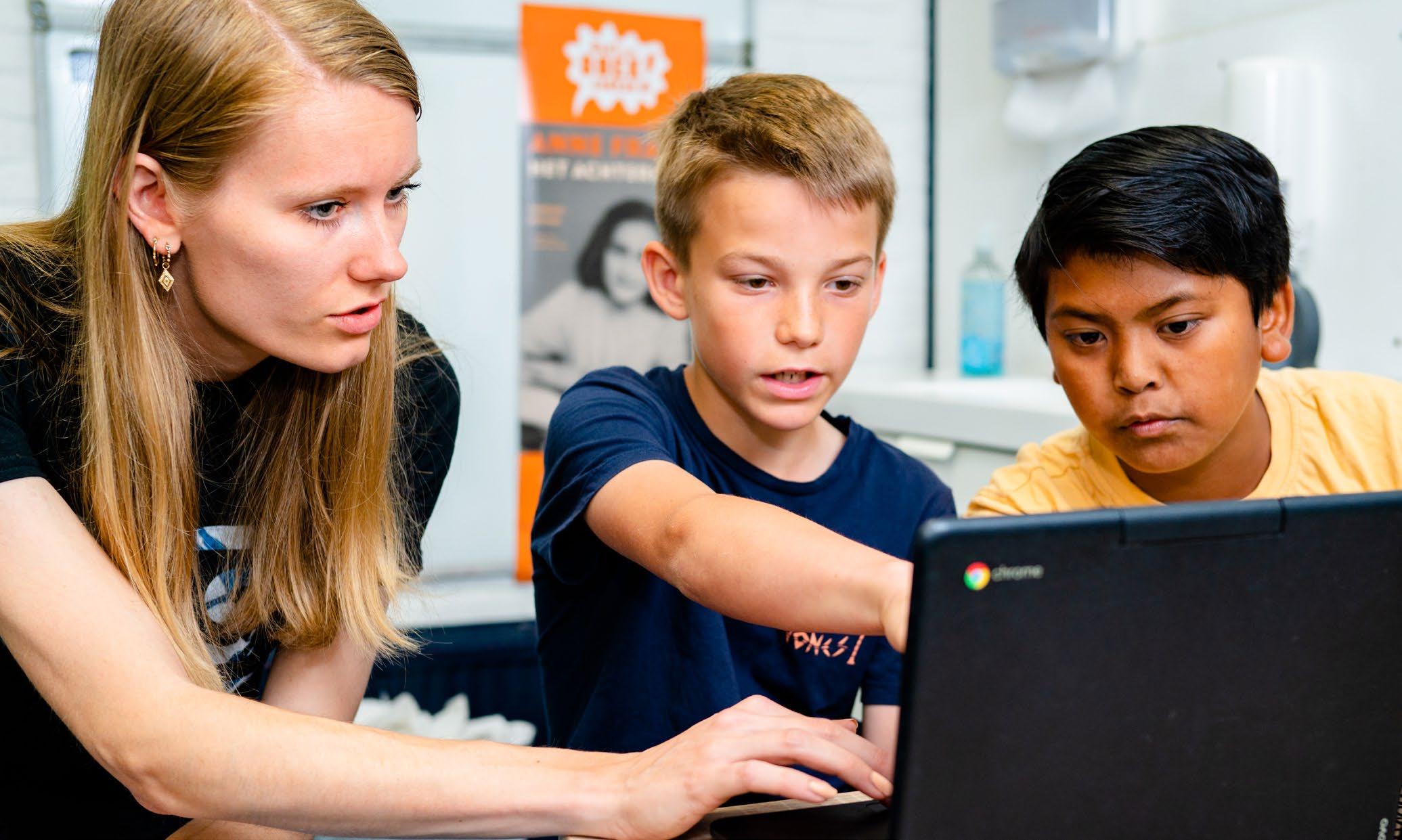 Kindcentrum De Morgenster in Zwolle, leerlingen werken samen met een lerares aan een laptop.
