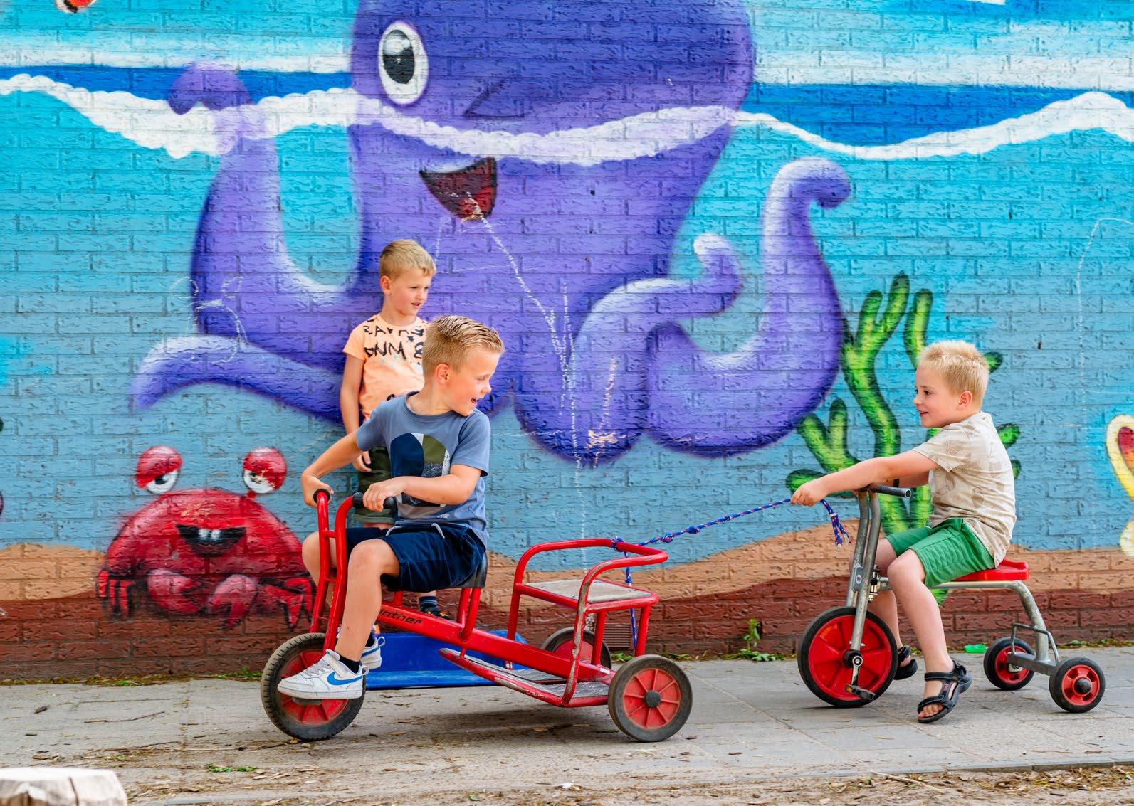 Kindcentrum De Morgenster in Zwolle met kinderen die spelen op het schoolplein met fietsen.